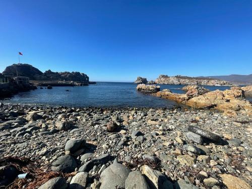 a rocky shoreline with rocks and the water at Casa Caleta Vieja Pichidangui in Los Vilos