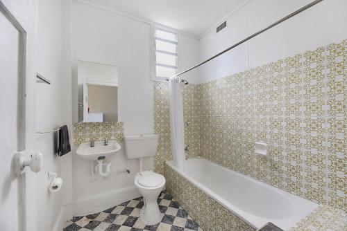 a bathroom with a toilet and a tub and a sink at 35 Wilson Avenue Dicky Beach QLD in Caloundra