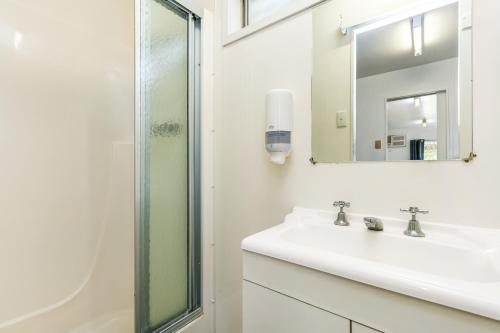 een witte badkamer met een wastafel en een spiegel bij BIG4 Breeze Holiday Parks - Port Elliot in Port Elliot