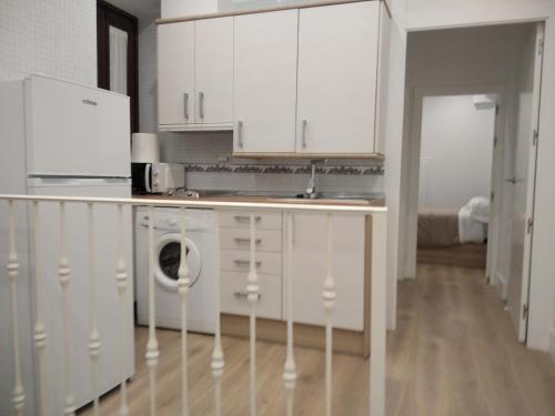 uma cozinha com armários brancos e uma máquina de lavar roupa em El PORTON DE LA BELLOTA - CON PARKING GRATIS - EN EL CENTRO DE TOLEDO em Toledo