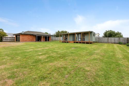 a large yard with a house and a fence at Virtue Haven - Whatuwhiwhi Holiday Home in Tokerau Beach
