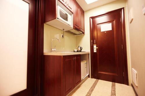 una pequeña cocina con fregadero y puerta de madera en Sunny Private Apartment Hotel Of Grand Continental, en Guangzhou