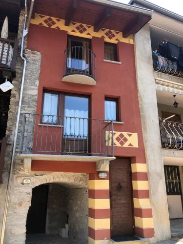 a red building with a balcony and a courtyard at Casa di Nonna in Entracque