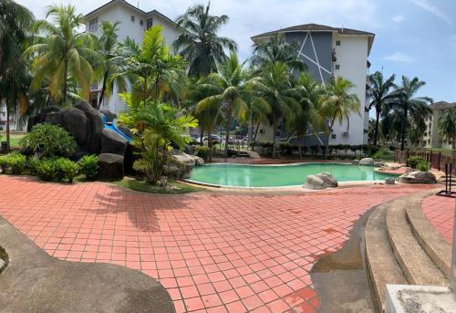a resort swimming pool with palm trees and a building at Penthouse 4 Bedroom Seaview in Port Dickson