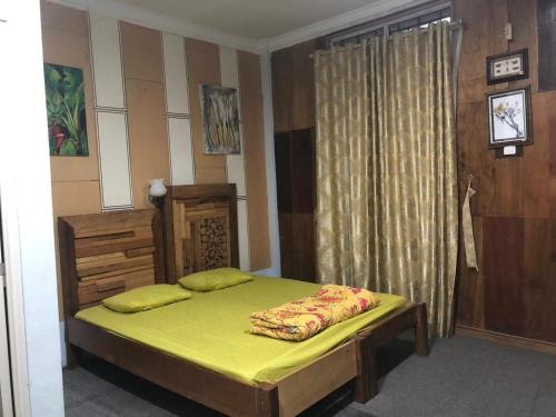 una camera da letto con un letto con lenzuola gialle e una finestra di Friendjoss Homestay Laugumba RedPartner a Berastagi