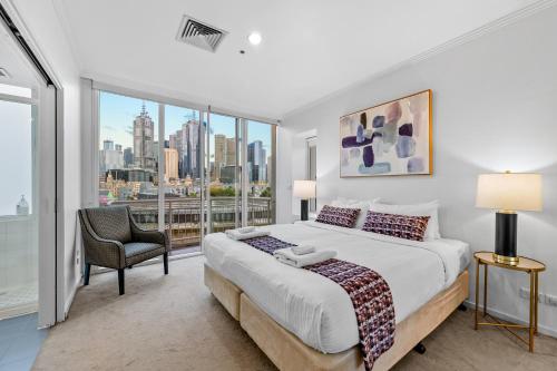 um quarto com uma cama grande e uma janela grande em Exclusive Stays - Southgate 28 em Melbourne