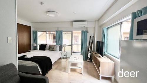 a bedroom with a bed and a tv and a couch at Maison Milano Nakatsu Apartment in Osaka
