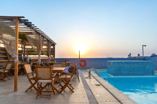 a patio with a table and chairs next to a swimming pool at Ivory Inn Hotel Doha Qatar in Doha