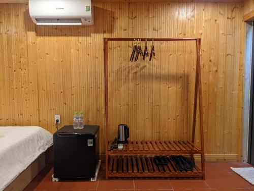 a room with a wooden wall with a bed and a refrigerator at Kim's Garden in Con Dao