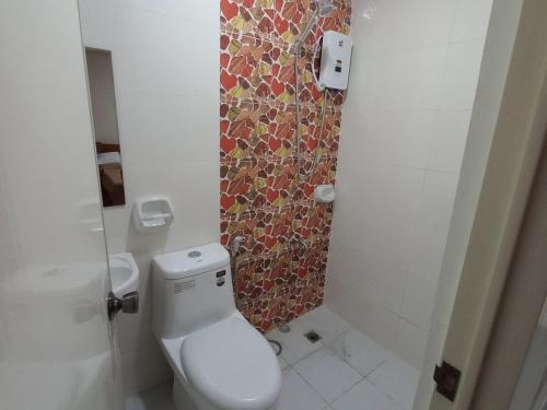a bathroom with a toilet and a mosaic wall at Visita highland Inn in Baguio