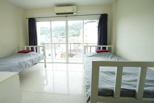 two beds in a room with a window at Bedbox Hostel in Patong Beach