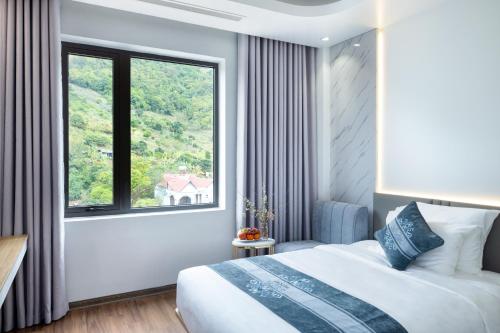 a bedroom with a bed and a large window at Glenda Tower Moc Chau Hotel in Mộc Châu