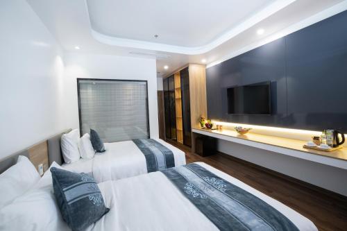 a hotel room with two beds and a flat screen tv at Glenda Tower Moc Chau Hotel in Mộc Châu