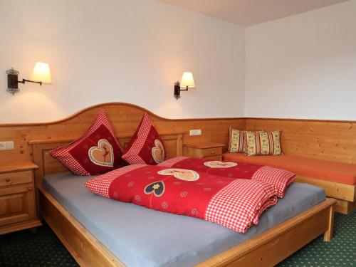 a bedroom with a bed with red and white pillows at Apartments Filzsteinalm, Hochkrimml in Kirchdorf