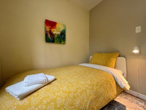 1 dormitorio con 1 cama y una pintura en la pared en Sunshine Guest House Yellowknife, en Yellowknife