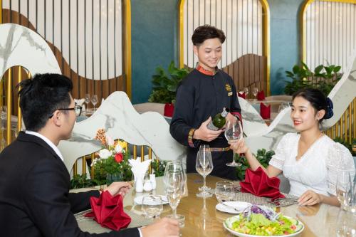a group of people sitting around a table in a restaurant at Glenda Tower Moc Chau Hotel in Mộc Châu