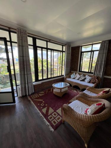 a living room with a couch and chairs and windows at Avocado Accommodations in Khadkagaon