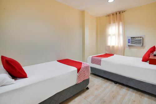 duas camas num quarto de hotel com almofadas vermelhas em OYO 912 Fb Suites 