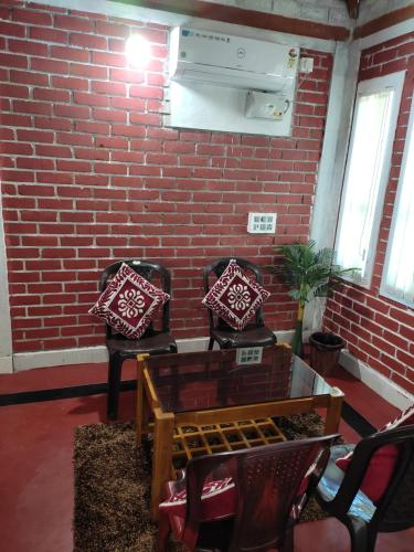 a room with two chairs and a brick wall at Gruham Malpe Beach Homestay Udupi in Malpe