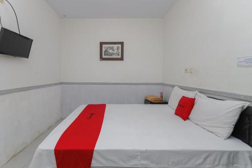 1 dormitorio con 1 cama con almohadas rojas y blancas en RedDoorz near Stasiun Malang Kota Lama 2, en Malang