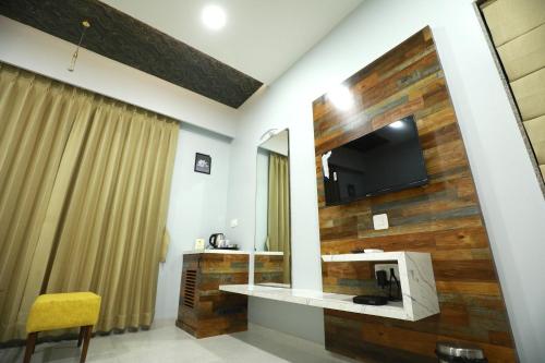 een hotelkamer met een televisie en een spiegel bij HOTEL THE GRANDLADHUKARA in Dwarka