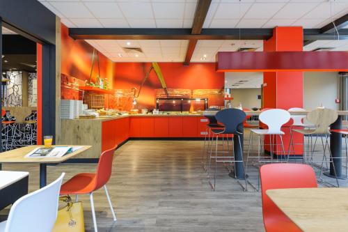 a restaurant with orange walls and tables and chairs at ibis Hotel Erfurt Altstadt in Erfurt