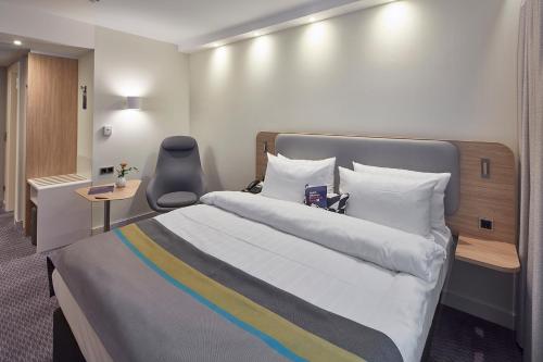 a bedroom with a large bed and a chair at Holiday Inn Express - Merzig by IHG in Merzig