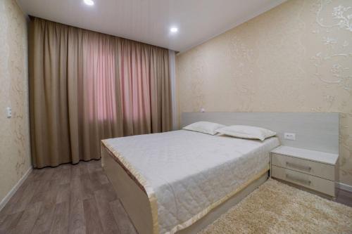 a bedroom with a white bed and a window at Квартира in Temirtaū