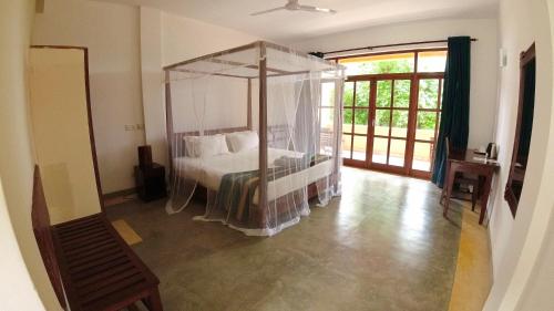 a bedroom with a bed with a canopy at Esprit d'Ici Hotel in Mirissa