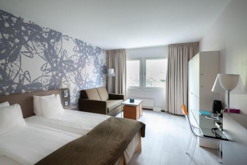 Quality Hotel Luleå في لوليا: غرفه فندقيه بسرير وكرسي