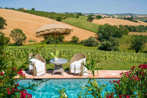 a pool with chairs and an umbrella and a table at CasaVostra - Ambience Suites in Ostra Vetere