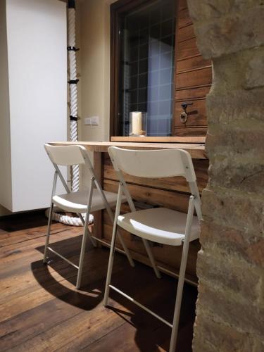 Dos sillas blancas sentadas en una mesa en una habitación en Incantevole monolocale en Perugia