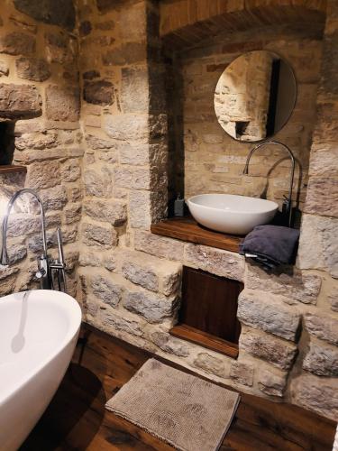 Baño de piedra con lavabo y espejo en Incantevole monolocale en Perugia