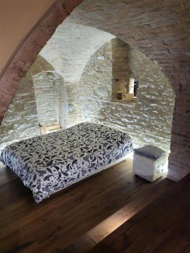 1 dormitorio con 1 cama en una pared de piedra en Incantevole monolocale en Perugia