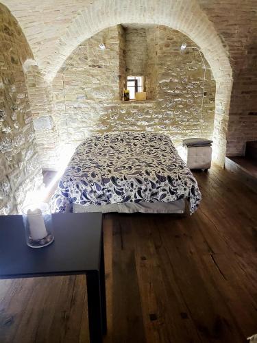 1 dormitorio con 1 cama en una pared de piedra en Incantevole monolocale en Perugia