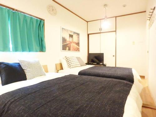 a bedroom with two beds and a green curtain at Dotonbori Mansion 401 in Osaka