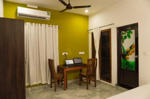 Zimmer mit einem Schreibtisch und einem Laptop-Computer. in der Unterkunft Je Sant O Casa Homestay in Kochi