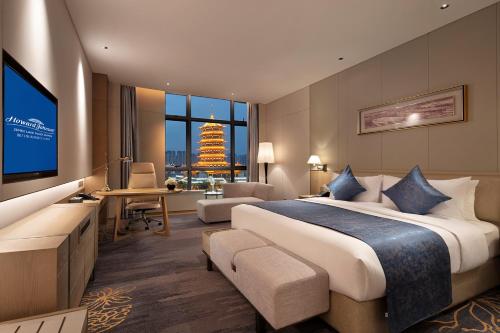 a hotel room with a large bed and a television at Howard Johnson by Wyndham Jimei Lake Plaza Xiamen in Xiamen