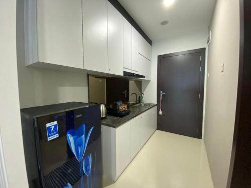 een keuken met witte kasten en een zwarte koelkast bij FORMOSA RESIDENCE - The Apartments 1 Bed Room 2003A in Nagoya