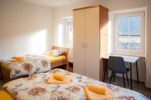 a small room with two beds and a desk and a chair at Relax House Soča in Bovec