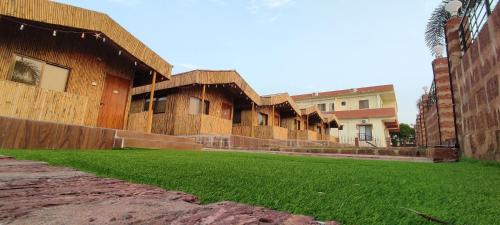 a group of buildings with grass in front of them at Mango Valley Resort Ganpatipule in Ratnagiri