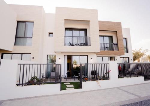 a white house with black fences and windows at Nasma Luxury Stays- Ras Al Khaimah in Ras al Khaimah