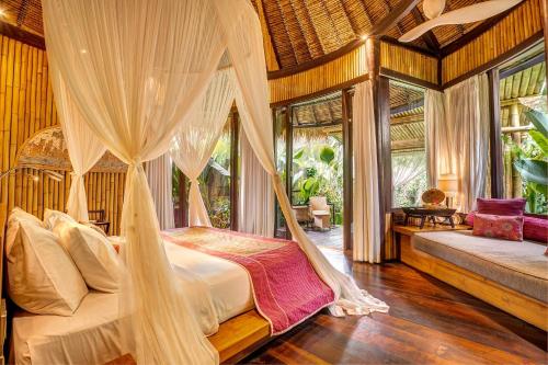 a bedroom with a bed with mosquito net at Fivelements Retreat Bali in Ubud