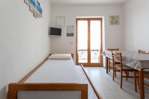 ein kleines Zimmer mit einem Bett, einem Tisch und einem Fenster in der Unterkunft Bilocale climatizzato a 50 m dalla spiaggia con posto auto privato in Lido Marini