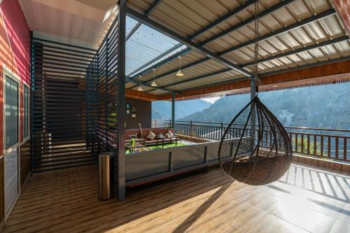 a room with a hammock on a balcony with a view at Zostel Plus Kareri in Dharamshala