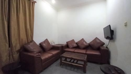 sala de estar con sofá marrón y TV en Gili Welldone Guesthouse, en Gili Trawangan