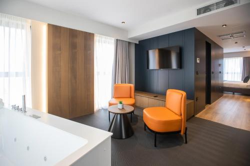 Habitación con 2 sillas de color naranja y mesa. en Hotel Elisa Tirana, Affiliated by Meliá en Tirana