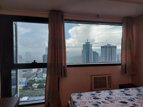 a bedroom with a large window with a view of a city at Romantic 1 Bedroom with Pool in Manila