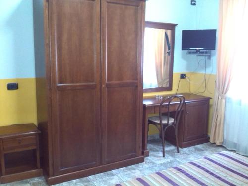 a large wooden cabinet next to a desk with a mirror at Hotel San Francesco Terme in Spezzano Albanese