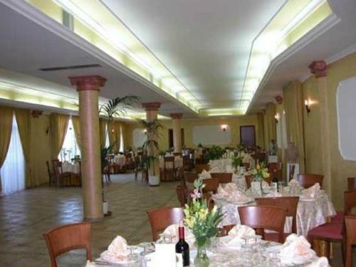 ein Esszimmer mit Tischen und Stühlen mit Blumen in der Unterkunft Hotel San Francesco Terme in Spezzano Albanese